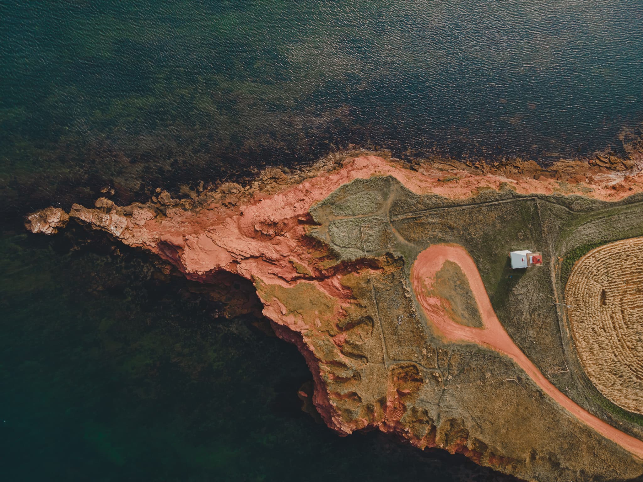 Aerial of a white house on a red cliff peninsula