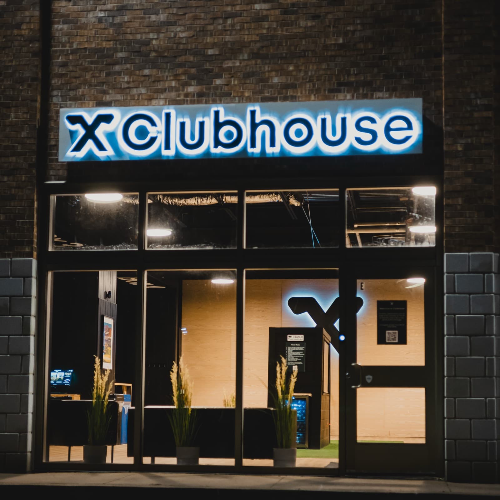A Clubhouse 24/7 location, lit storefront at night with 24-hour access
