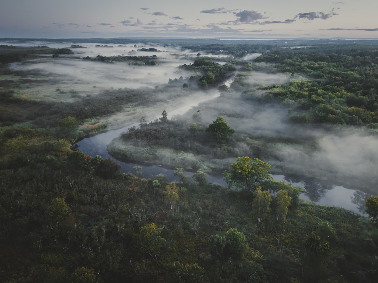Aerial drone photography by Belair Creative, a misty river valley at dawn